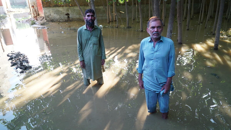 Due uomini in piedi con le gambe nell'acqua delle alluvioni