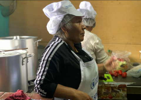 Older Peruvian lady in a WFP apron and hair net working in a kitchen