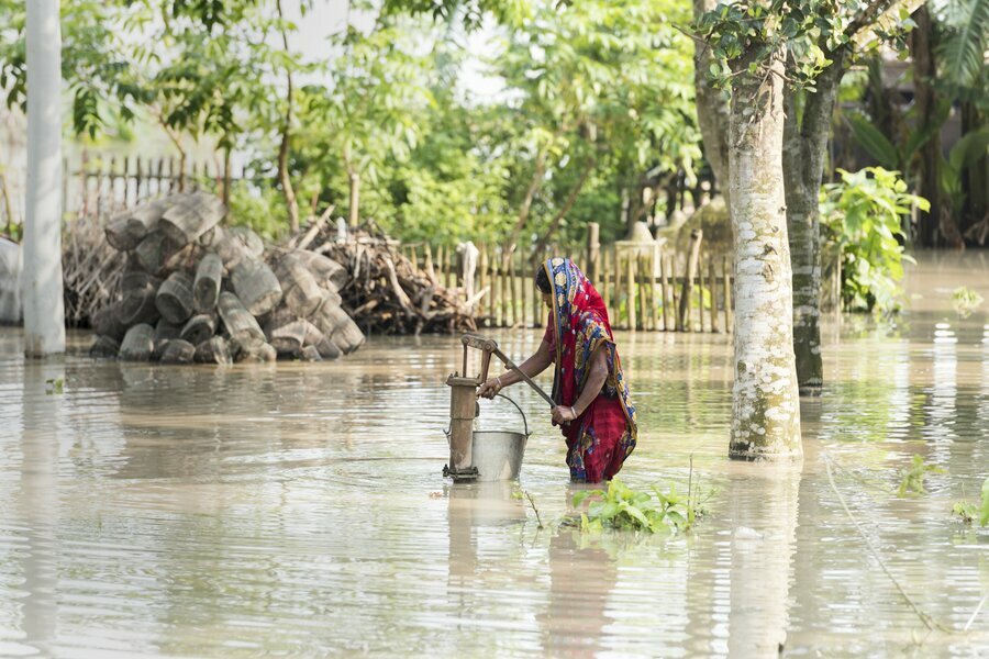 A woman fetches water after severe flooding in Kurigram District, Bangladesh. 