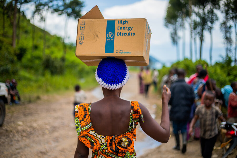 Donna cammina con una scatola di cibo del WFP sul capo.