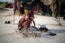  WFP/Balach Jamali. Donna cucina a terra in un ambiente distrutto dalle inondazioni 