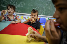 Bambini di Gaza mangiano del pane in una scuola dell'UNRWA
