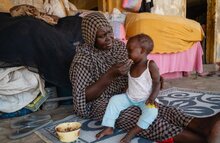 WFP/Abubaker Garelnabei. Donna dà da mangiare a una bambina la cui madre è in cerca di lavoro 