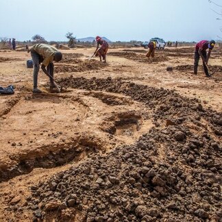 uomini lavorano la terra per fare mezze lune per la raccolta di acqua piovana